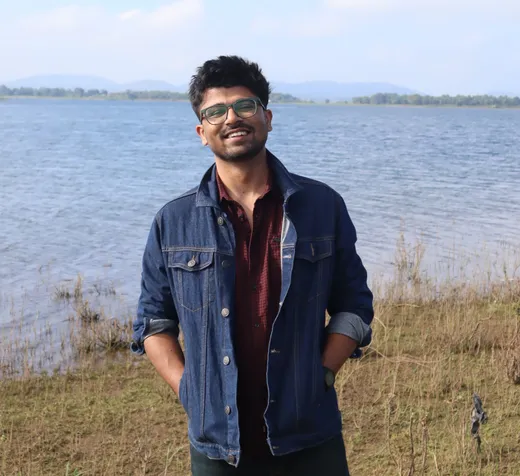Pranay Agarwal standing by a lake, hills in the distance